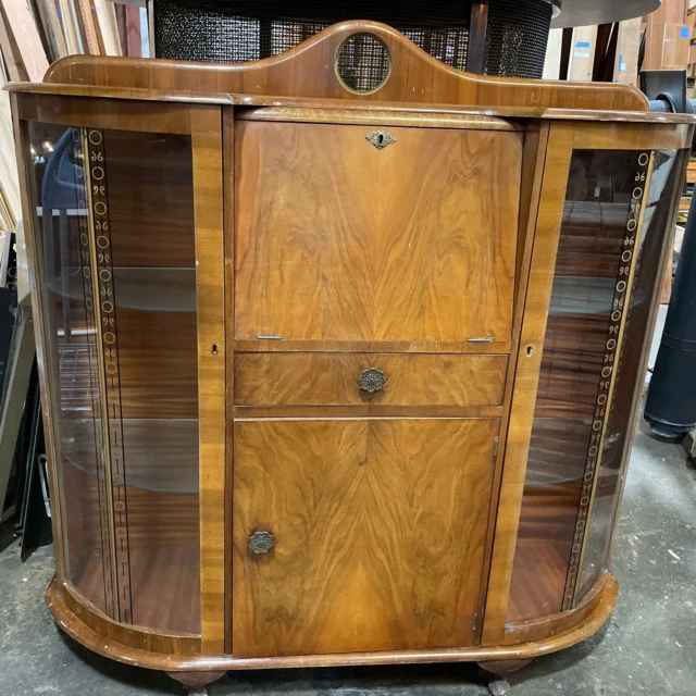This antique Art Deco-style walnut veneer secretary desk slash curio cabinet is an absolute steal for fans of unique and classy furniture! It features one pull down door with cubbies, one pull-out drawer, one lower cabinet door with two shelves and two side displays with glass decal decorations on each door. Could easily be used as a retro cocktail bar, or as a neat little desk with family heirlooms, photos, and collectables on display. Choose your own adventure!Measures 49.5"W x 51.25"H x 15"DKenmoreID: 93176$125You can place a 24 hour hold on this item by calling (425) 481-0245 and requesting a hold on item ID 93176#SecretaryCabinet #SecretaryDesk #Antique #Vintage #Retro #CocktailBar #Walnut #Cabinet #CurioCabinet #Curio #AntiqueFurniture #VintageFurniture #Earthwise #Kenmore #Salvage